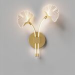 Wandlamp met 2 bloemen, de ene leunend naar links, de andere naar rechts, vastgehouden op een gouden voet. De stelen en bloemen verspreiden het licht.