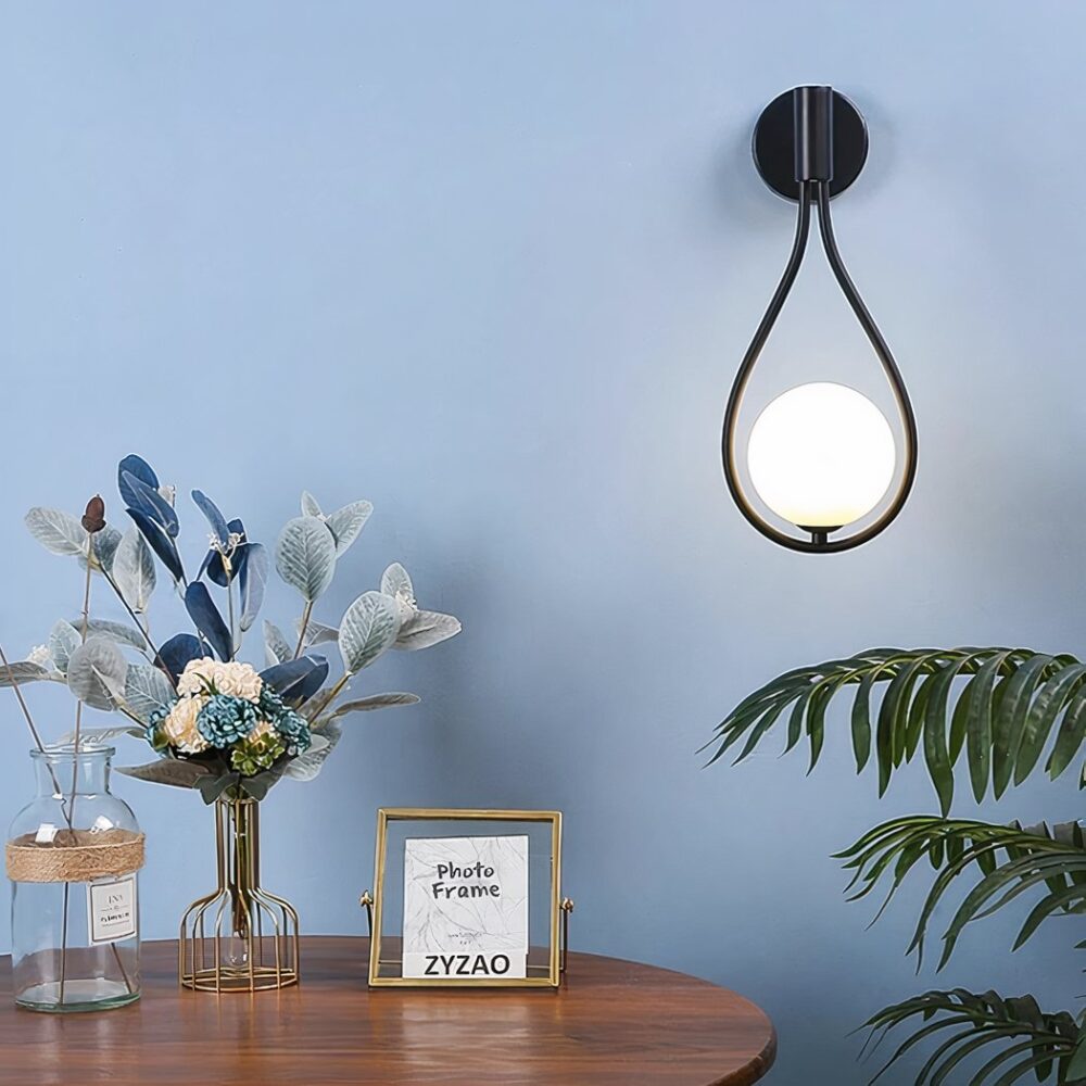 Een zwarte traanvormige wandlamp met een bollamp hing aan een blauwe muur in een woonkamer.
