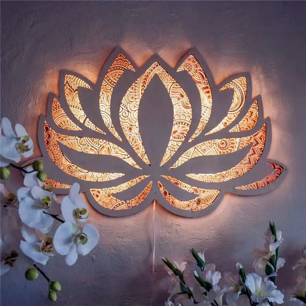 Mandala stijl lotusbloem wandlamp ingeschakeld, waardoor licht door het opengewerkte ontwerp valt. In de onderste hoeken van de afbeelding zijn geraniumachtige bloemen te zien.