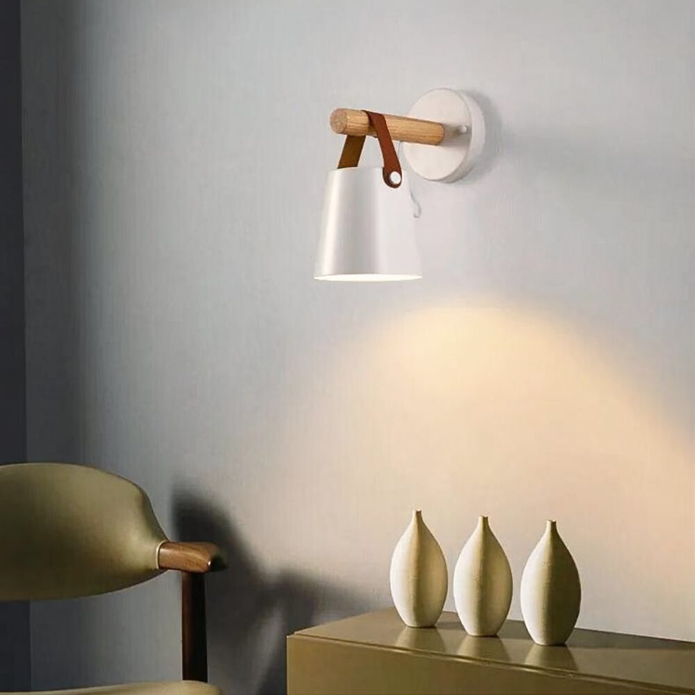 we zien een witte wandlamp met een kunstlederen band op een lichtgrijze muur