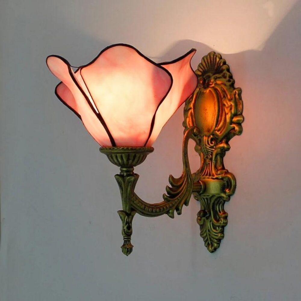 een roze wandlamp in Tiffany-stijl brandt op een lichtgrijze muur