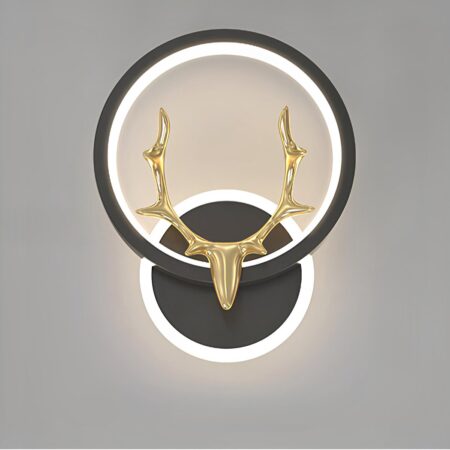 zwarte wandlamp, de steun is rond met een cirkel van licht eromheen. Het houdt een cirkel van licht in een zwarte cirkel waarop een gouden hertenkop is geplaatst. Op een grijze achtergrond.