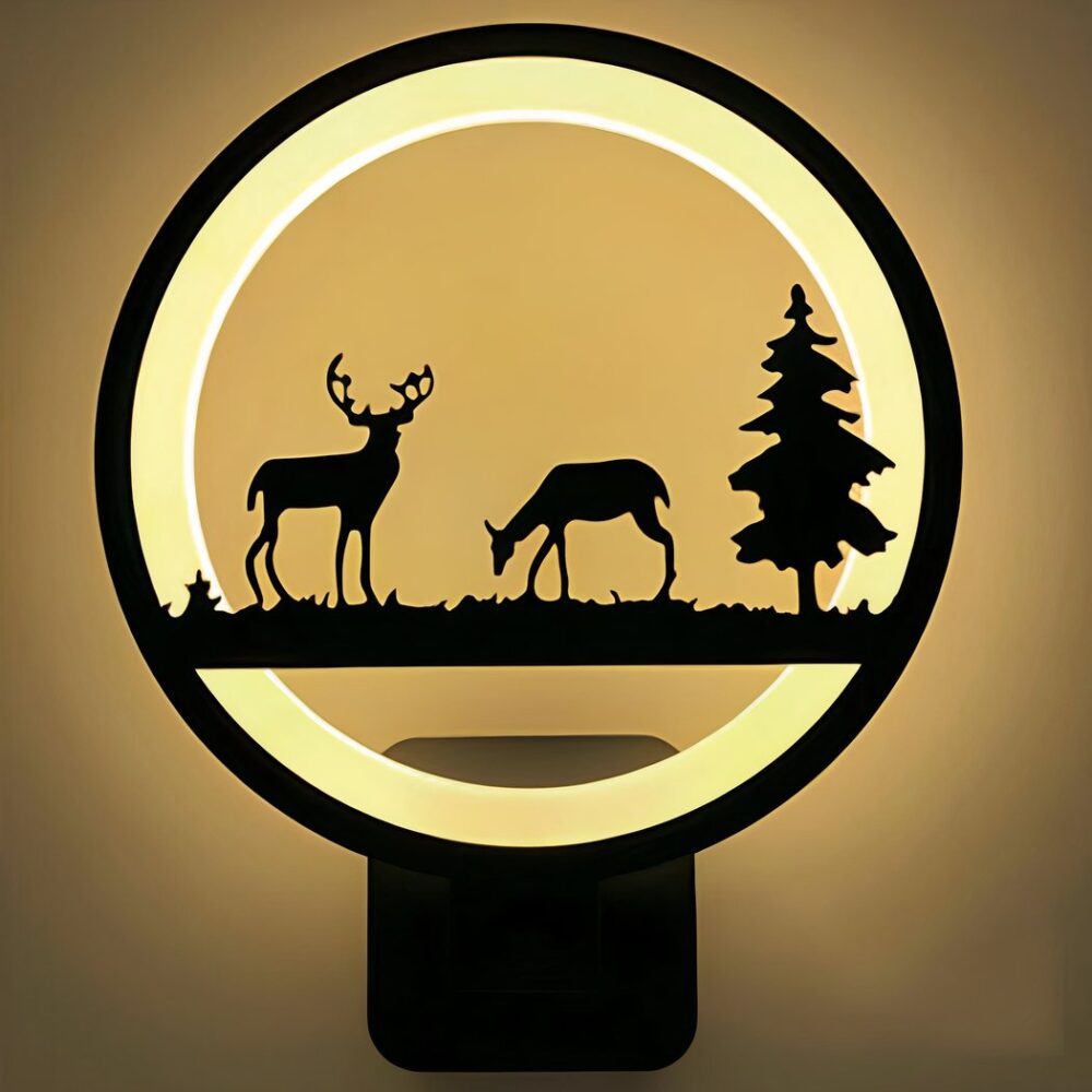 Ronde wandlamp met verlichte cirkel. De omtrek is zwart en de binnenkant is lichtgevend. In het midden van de cirkel een dierenscène met een rendier, een hinde en een dennenboom, alles in zwart.