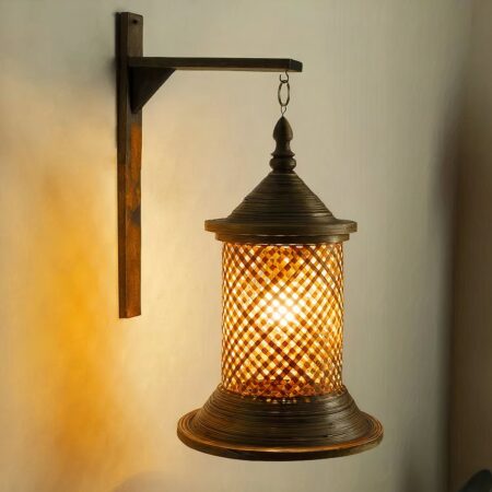 Deze handgeweven bamboe wandlamp is verlicht en hangt aan een beige muur.