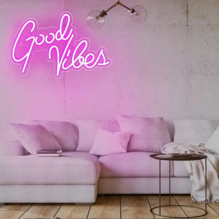 Good vibes neon wandlamp ingeschakeld en opgehangen aan een huiskamermuur boven een grote beige hoekbank.