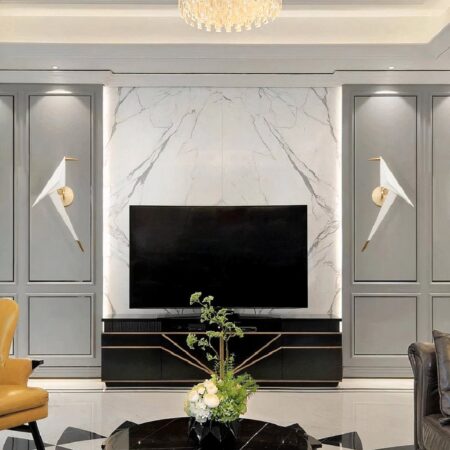 in een woonkamer met grijze muren staat in het midden een tv uit en aan elke kant een origami wandlamp in de vorm van een witte vogel