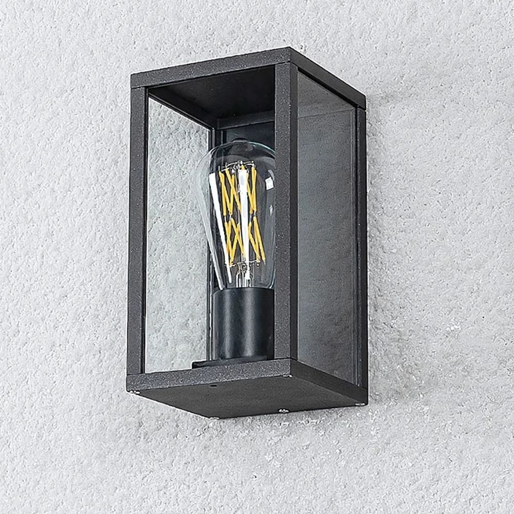 Buitenwandlamp met zichtbare gloeilamp in de vorm van een doos met zwarte metalen contouren en met de uitgeschakelde gloeilamp zichtbaar. Gemonteerd op een witte buitenmuur.